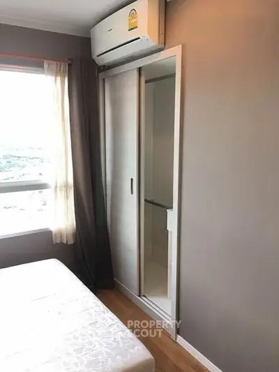 Cozy bedroom with air conditioning and sliding closet doors, featuring a large window for natural light.
