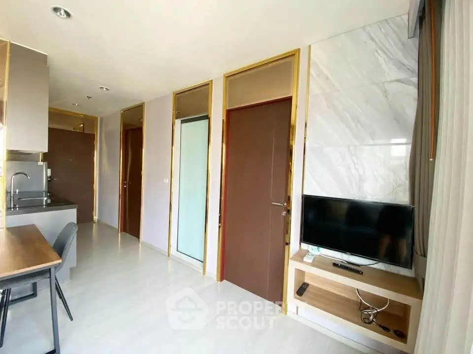 Modern apartment interior with sleek kitchen and cozy living area featuring a wall-mounted TV.