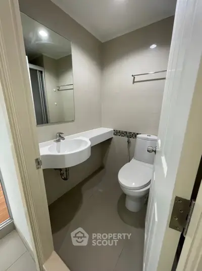 Modern bathroom with sleek fixtures and minimalist design, featuring a wall-mounted sink and contemporary toilet.