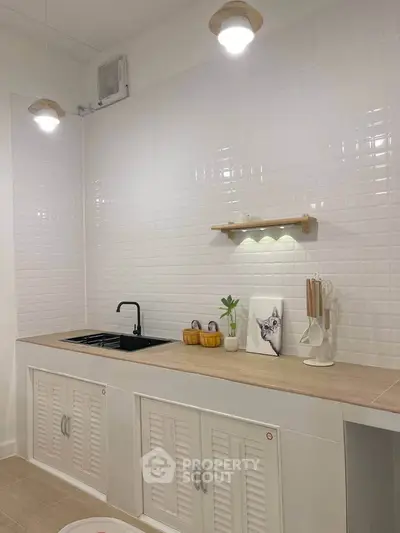 Modern kitchen with sleek black sink and minimalist decor, featuring white tile backsplash and wooden accents.