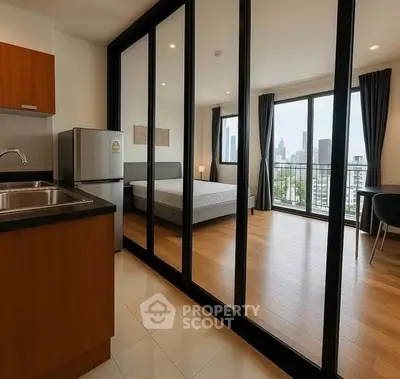 Modern studio apartment with city view, featuring mirrored wardrobe and compact kitchen.