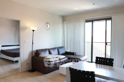 Modern living room with leather sofa, dining table, and balcony access in a stylish apartment.