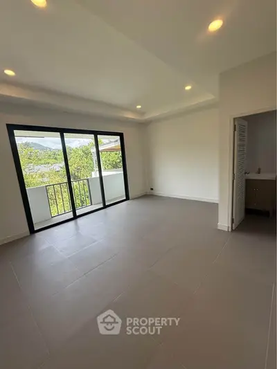 Spacious living room with large windows and balcony view, perfect for natural light lovers.