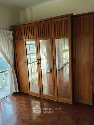 Spacious bedroom with elegant wooden wardrobe and large windows