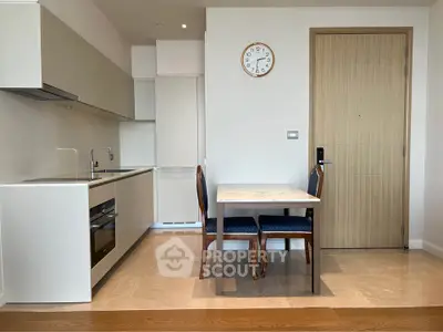 Modern kitchen with dining area featuring sleek cabinetry and elegant wooden table.