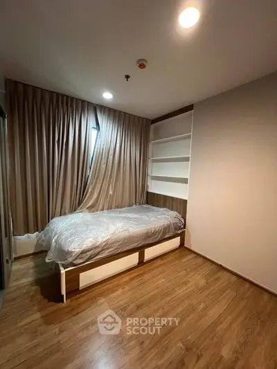 Cozy bedroom with wooden flooring and built-in shelves, perfect for modern living.