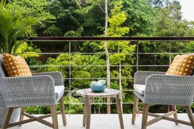 Charming balcony with cozy seating and lush green view, perfect for relaxation.