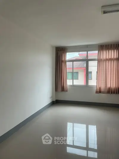 Spacious empty room with large window and tiled floor, perfect for customization.