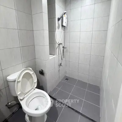 Modern bathroom with tiled walls and electric shower in a real estate property.