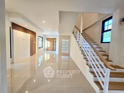 Spacious modern living room with sleek staircase and large windows, perfect for family gatherings.