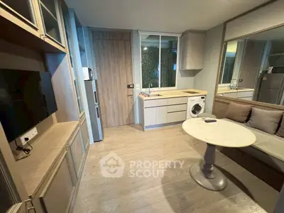 Modern compact living room with integrated kitchen and washing machine, featuring sleek wooden flooring and stylish decor.