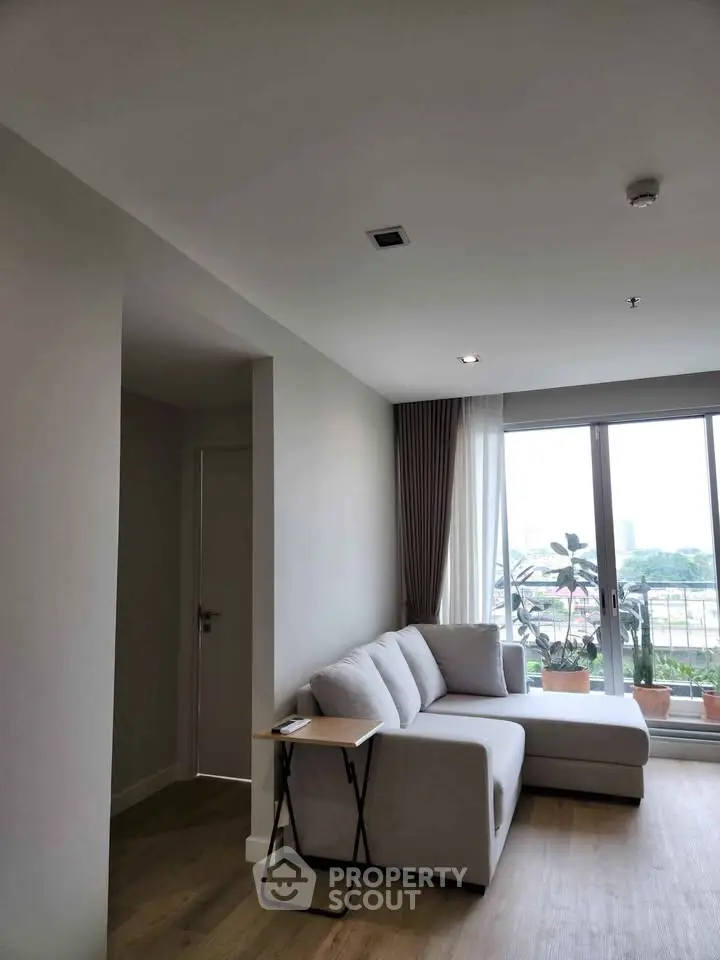 Modern living room with large windows and cozy sectional sofa, offering a bright and inviting atmosphere.