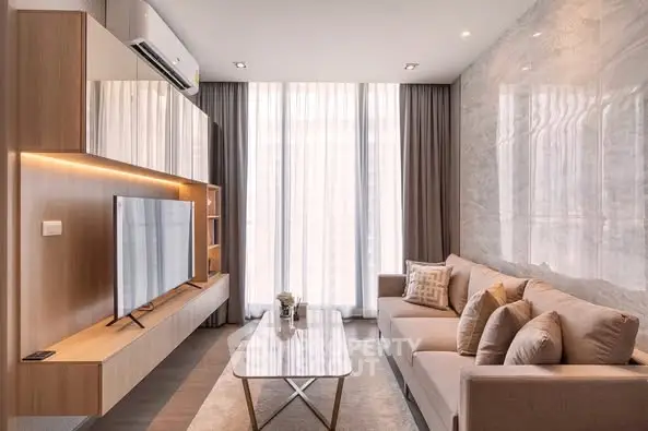 Modern living room with sleek furniture and large TV, featuring elegant curtains and ambient lighting.