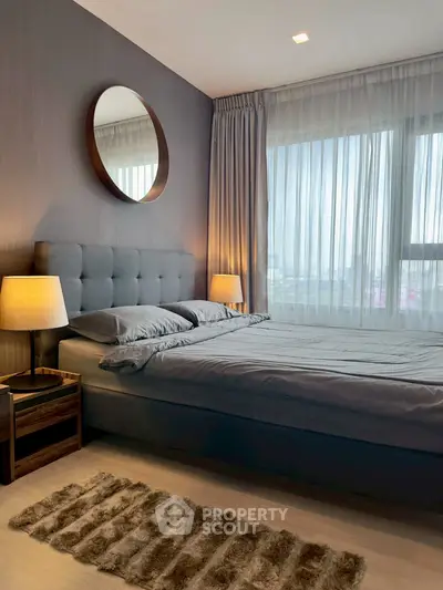 Modern bedroom with stylish decor and large window offering natural light.
