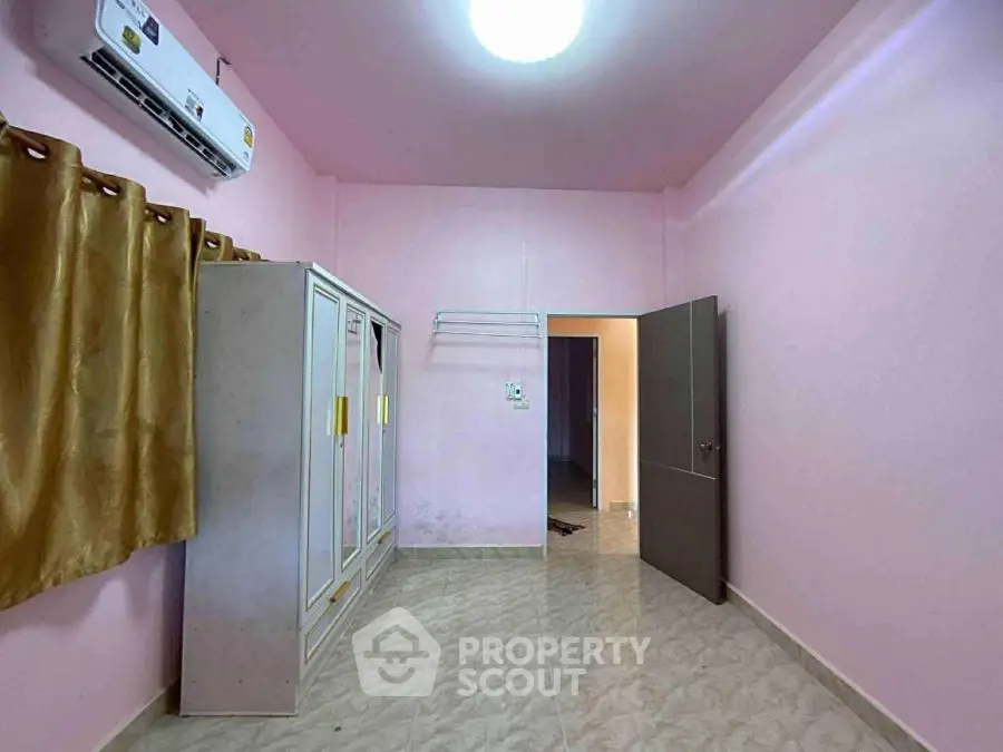Spacious bedroom with pink walls, wardrobe, and air conditioning unit.