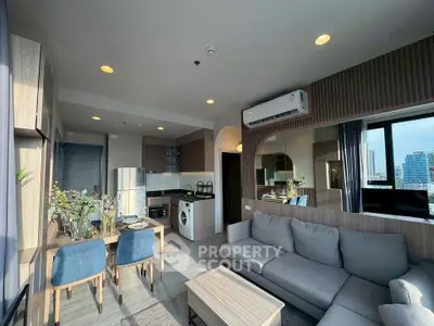 Modern living room with open kitchen, stylish decor, and city view.