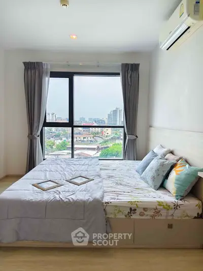 Bright bedroom with large window offering stunning city view, featuring modern decor and cozy bedding.