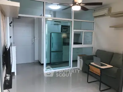 Modern living room with glass partition, ceiling fan, and compact kitchen area.