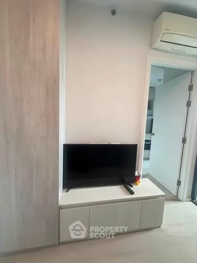 Modern living room with sleek TV setup and air conditioning in a stylish apartment.