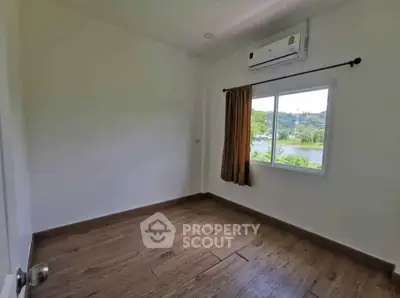 Spacious empty room with wooden flooring and scenic window view, perfect for customization.