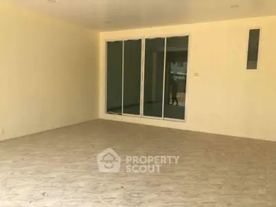 Spacious empty room with large sliding glass doors and tiled flooring, perfect for customization.