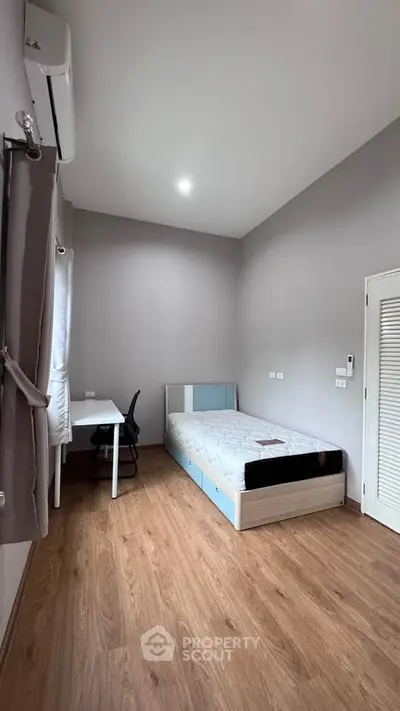 Modern minimalist bedroom with wooden flooring and sleek furniture