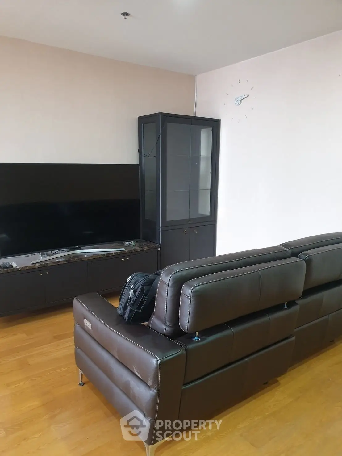 Spacious living room with modern leather sofas and large flat-screen TV, perfect for relaxation.