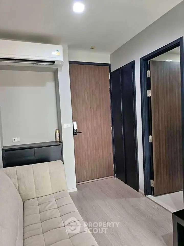 Modern apartment entrance with sleek wooden door and cozy sofa, perfect for urban living.