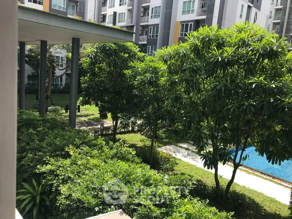 Lush garden view with modern apartment building and pool