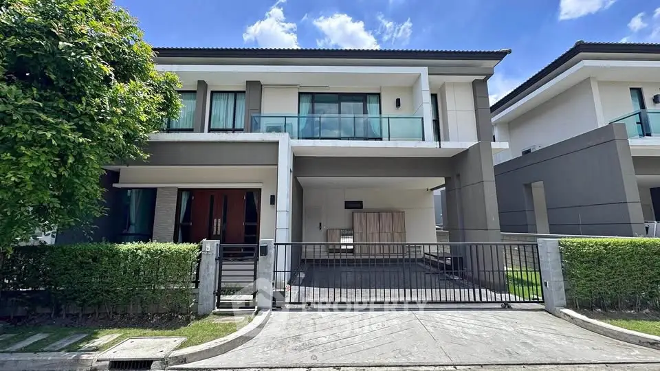 Modern two-story house with sleek design and spacious driveway under clear blue sky.