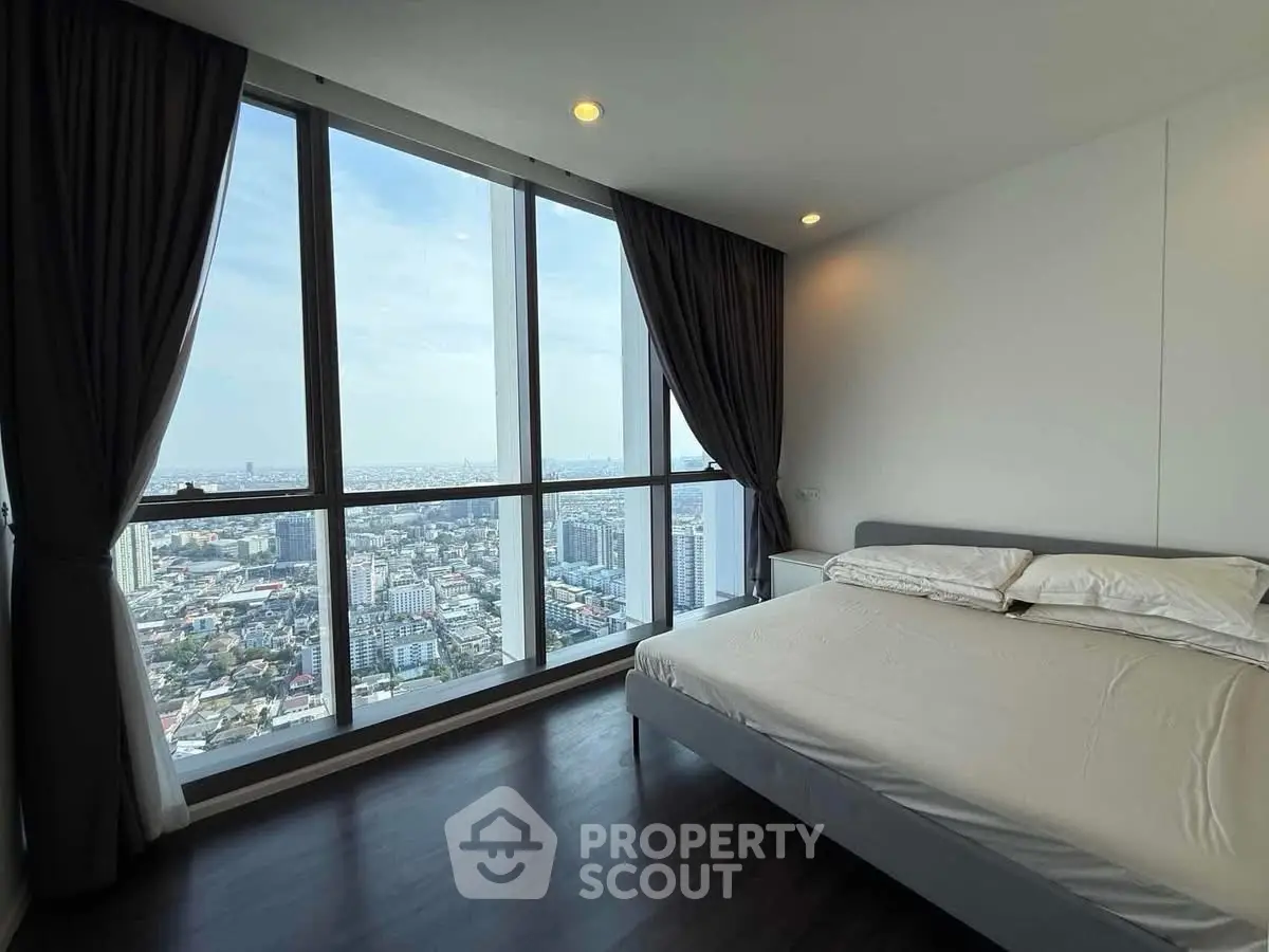 Luxurious bedroom with panoramic city view from floor-to-ceiling windows, featuring elegant decor and natural light.