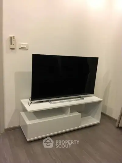 Modern living room with sleek TV stand and flat-screen television on wooden flooring.