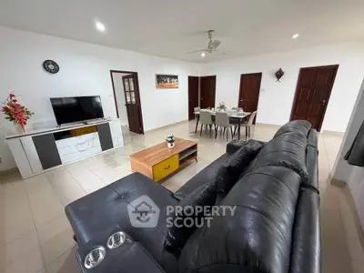 Spacious living room with modern leather sofa and dining area, perfect for family gatherings.