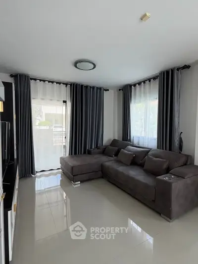 Modern living room with sleek gray sofa and large windows for natural light.