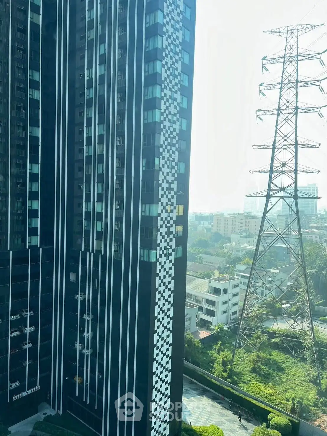 Modern high-rise building with unique facade next to power line tower