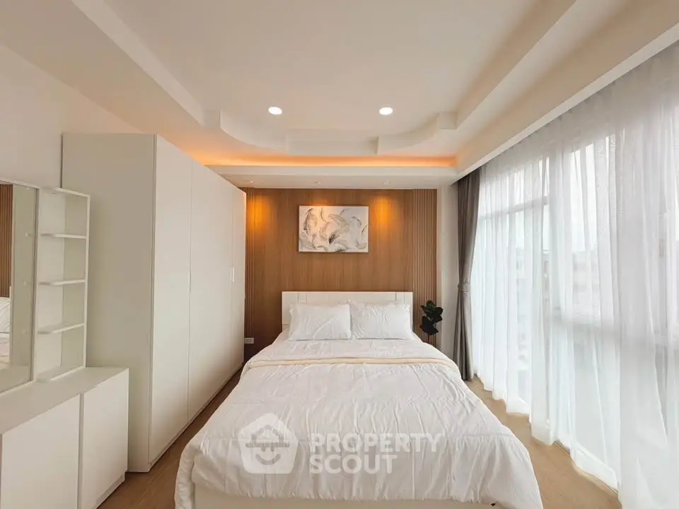 Spacious modern bedroom with elegant lighting and large windows for natural light.