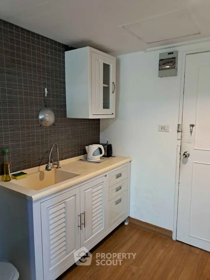 Compact kitchen with white cabinets and modern appliances in cozy apartment