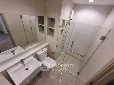 Modern bathroom with glass shower enclosure and sleek fixtures in a contemporary apartment.