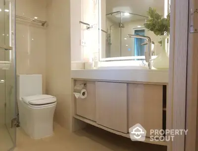 Modern bathroom with sleek finishes, featuring a large mirror, under-sink cabinetry, and a glass-enclosed shower area, exuding a clean and serene ambiance.