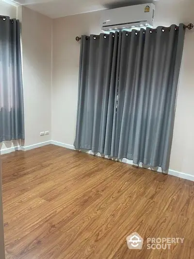 Spacious empty room with wooden flooring and air conditioning