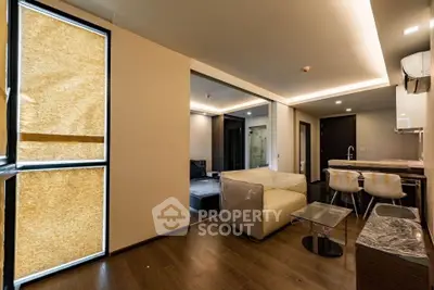 Modern open-layout living room with stylish kitchen and dining area, featuring sleek furniture and ambient lighting.