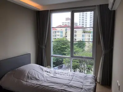 Cozy bedroom with large window offering a city view, modern design and ample natural light.