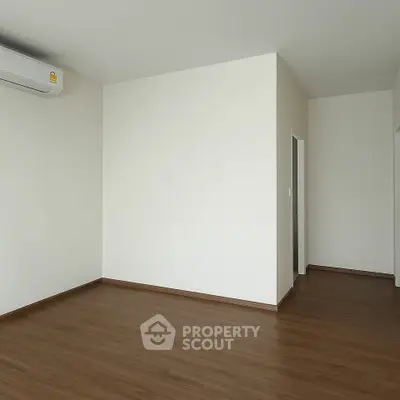 Spacious empty room with wooden flooring and air conditioning unit, perfect for customization.