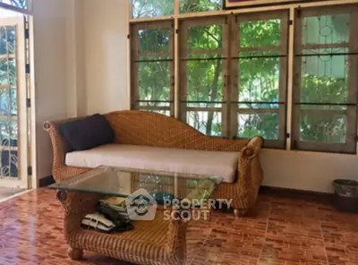 Charming living room with wicker furniture and garden view, perfect for relaxation.