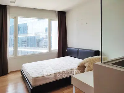 Modern bedroom with large windows and city view, featuring a comfortable bed and sleek design.