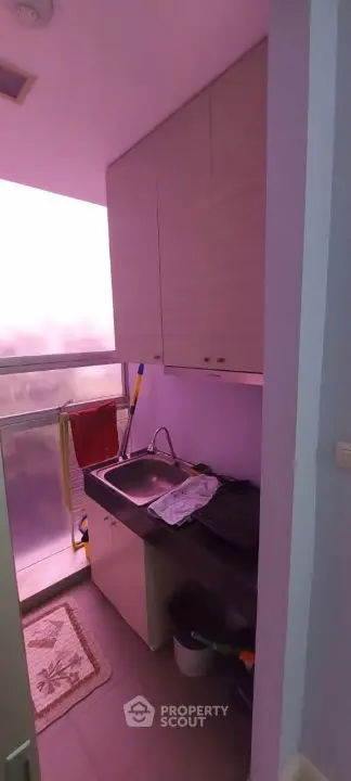 Compact kitchen area with sink and storage cabinets, featuring a frosted glass window for natural light.