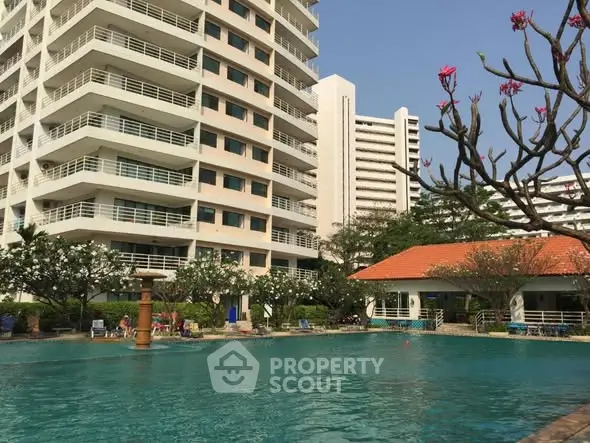 Luxurious residential building with poolside view and lush garden surroundings.