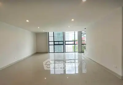 Spacious modern living room with large windows and glossy tiled floors