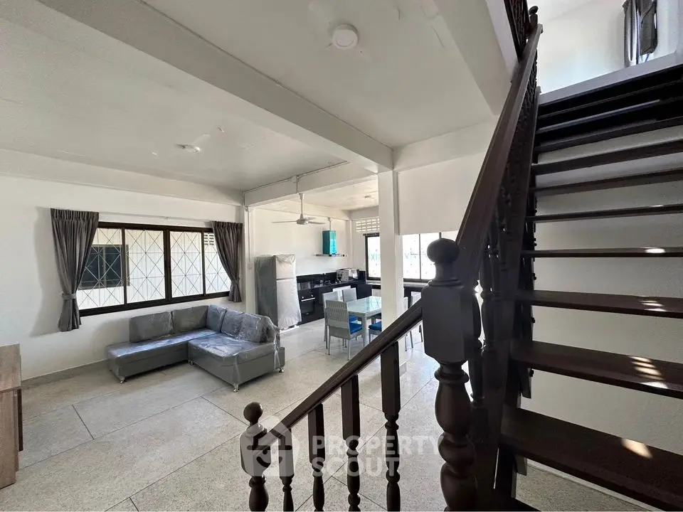 Spacious open-plan living area with modern staircase and natural light