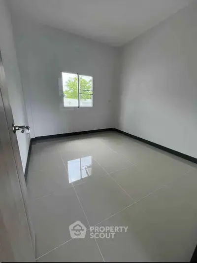 Spacious empty room with glossy tiled floor and large window, perfect for customization.